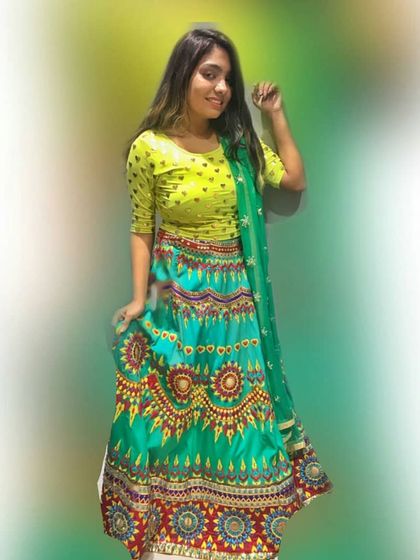 A vibrant and colorful lehenga perfect for a mehendi or Navratri celebration. The combination of a lime green blouse and a multi-patterned turquoise skirt creates a fun and festive look.