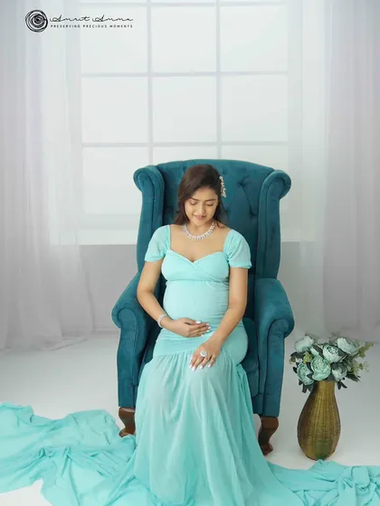 A moment of quiet reflection. This solo portrait, with the soft light and elegant teal armchair, is all about capturing the serene and powerful journey of a mother to be.