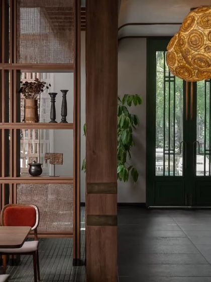 A detail shot focusing on the custom wooden partitions with cane webbing. These elements help to create intimate dining zones while allowing light and air to flow through the space, adding to the restaurant's open feel.