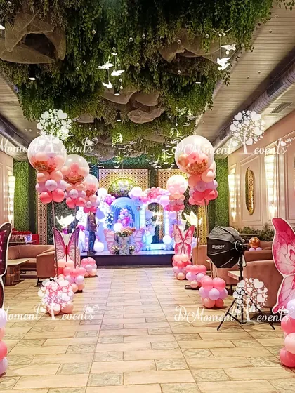 The entire venue is transformed into a butterfly garden with themed balloon pillars and hanging decor, creating an immersive experience from the moment guests walk in.