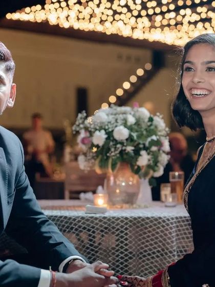 A candid moment of the couple at their reception. The decor in the background features a beautiful canopy of fairy lights, adding a soft, romantic glow to the evening.