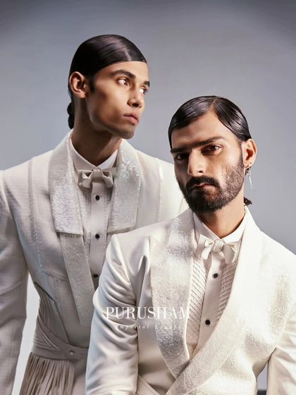 A close-up portrait of two models in my modern white suits. The textured lapels and matching bow ties add a layer of sophistication to these perfectly pure ensembles.