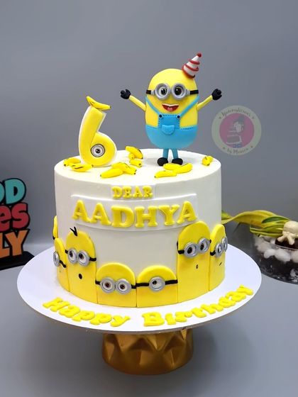 A fun Minion-themed cake for Aadhya's 6th birthday, with a happy Minion on top and little Minions peeking around the base.