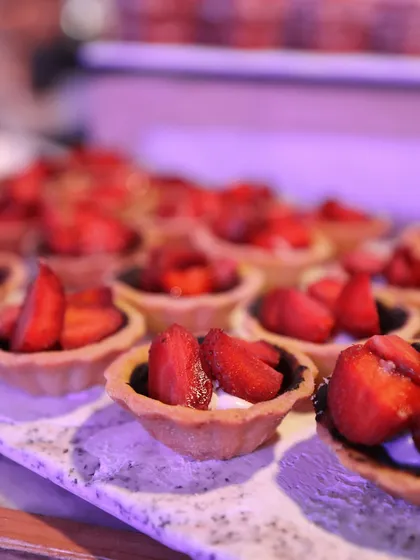 Miniature strawberry tarts, filled with cream and topped with fresh, juicy strawberries. A simple, fresh, and delicious bite.
