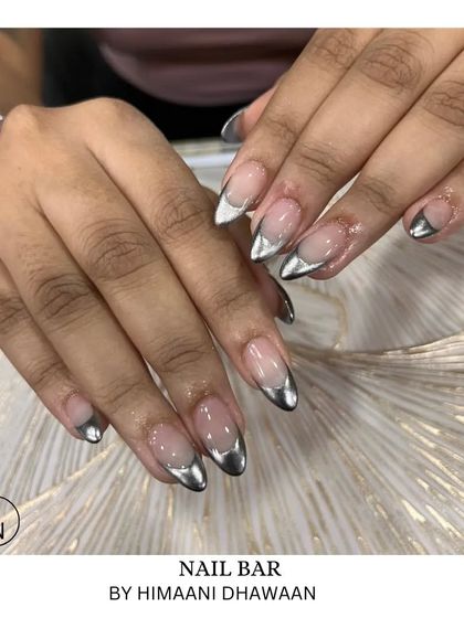 A sharp and modern look with silver chrome French tips on long, pointed almond-shaped nails.
