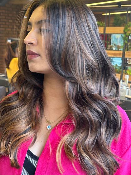 A close-up of a beautiful balayage, showing the intricate blend of colors. The waves highlight the different tones, from dark brown to light ash.