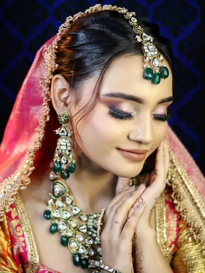 A bride in a multi-colored lehenga with stunning emerald jewelry. This look shows how to work with a vibrant color palette to create a cohesive and breathtaking bridal style.