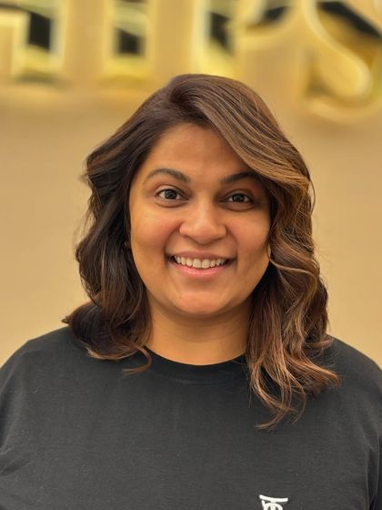 A smiling client showing off her new creative color. The warm tones and soft waves create a look that is both stylish and sophisticated.