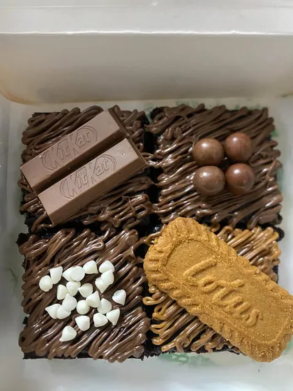 My four-piece assorted brownie box is perfect for sampling different flavors. This box includes KitKat, chocolate balls, white chocolate chip, and Lotus Biscoff toppings on my classic fudgy brownie base.