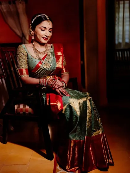 A full view of the client in her sage green and red saree. The custom blouse and classic drape create an aura of timeless elegance.