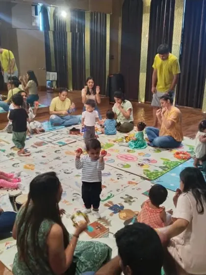 A little one takes center stage with egg shakers while the group supports him. This shows how my classes help build confidence and social skills in a group setting.