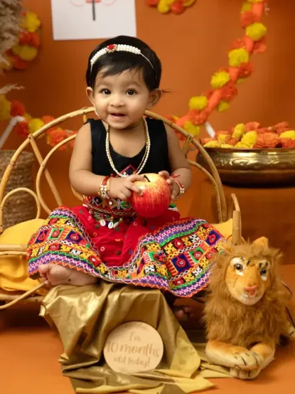 A happy moment with an apple prop. The warm, earthy tones of the Dussehra set create a beautiful and inviting atmosphere for these festive portraits.