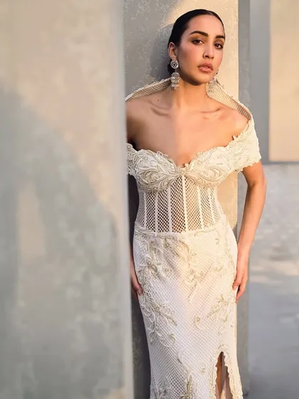 This embroidered mesh corset gown is a bold play of contrast. Crowned with a sculptural hood, it is sheer yet strong, delicate yet commanding.