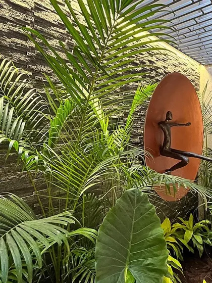 Where art and nature dance. This serene sunken basement court is enveloped in lush foliage, with a joyful dancing sculpture that seems to leap from the rustic chiselled stone backdrop.