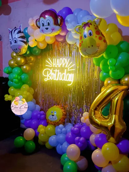 A colorful jungle-themed balloon ring with animal foils and a neon 'Happy Birthday' sign, perfect for a 4th birthday.