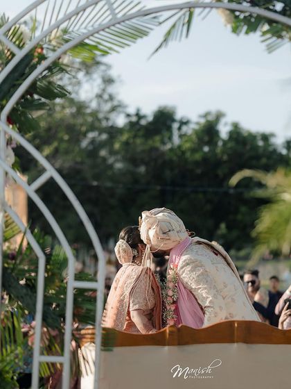 A sweet, stolen kiss under the wedding arch, a perfect candid moment of love and celebration.