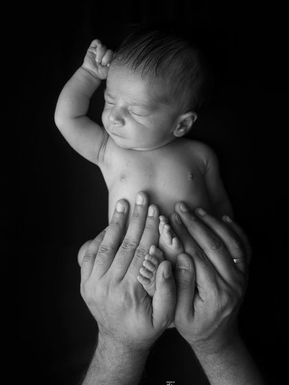 A newborn's tiny foot resting in their father's hand. This detailed black and white shot is a beautiful way to remember just how small they once were.