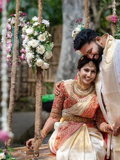 A tender moment on the swing, the groom leaning his head on the bride's shoulder, surrounded by a cascade of flowers.