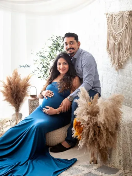 This expecting mother looks like a queen in a beautiful blue gown. The boho setup adds a touch of earthy elegance to her maternity portrait.
