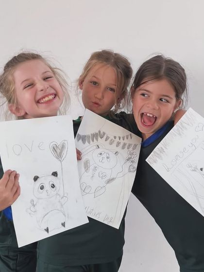 Three friends joyfully display their unique panda sketches, each one reflecting their individual personality and creative flair.