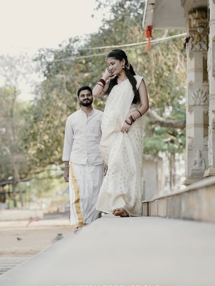 A candid moment of a bride-to-be in a traditional white saree, walking down steps as her partner looks on.