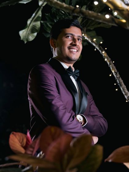 A handsome portrait of the groom in a sharp purple tuxedo, smiling confidently. We love taking individual portraits that let each person's personality shine.
