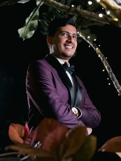 A handsome groom in a purple tuxedo, smiling during his reception.