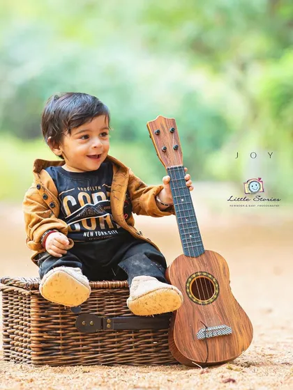 Finding his rhythm. Musical props like this ukulele are a wonderful way to engage a child and capture their natural curiosity and playful expressions.