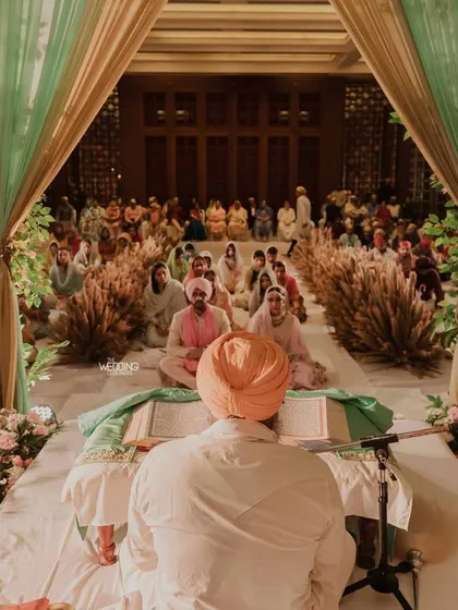 A serene Anand Karaj ceremony held in Goa. The decor combines mint green drapes with natural pampas grass, creating a soft and earthy environment for the sacred Sikh wedding ceremony.