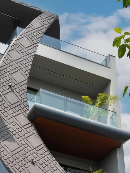 A close-up of the wave-form facade, showing the texture of the concrete grooving and the clean lines of the glass balcony railings. The design is both sculptural and functional.