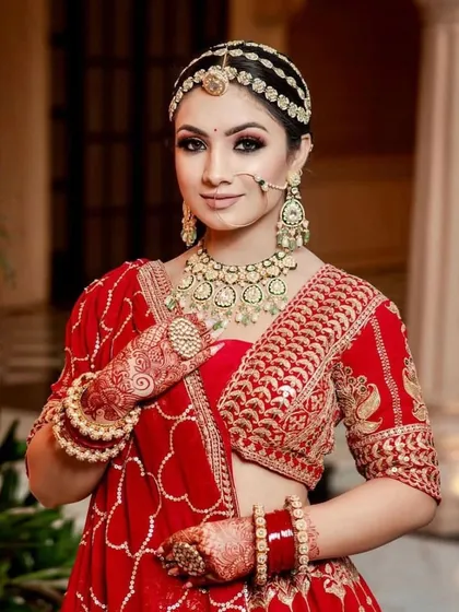 A classic red bridal look for the modern bride. The makeup features defined, kohl-rimmed eyes and a matte red lip, paired with a traditional matha patti for a regal and timeless appearance.