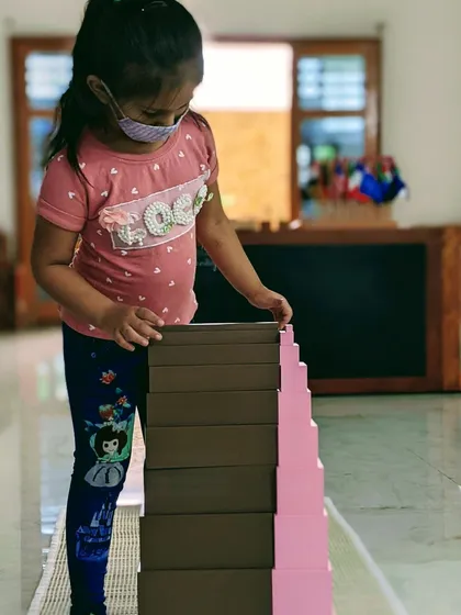 A child experiences the relationship between size and dimension by combining two classic Montessori sensorial materials, the Pink Tower and the Brown Stairs. This hands-on work builds a concrete foundation for future mathematical understanding and sharpens visual discrimination.