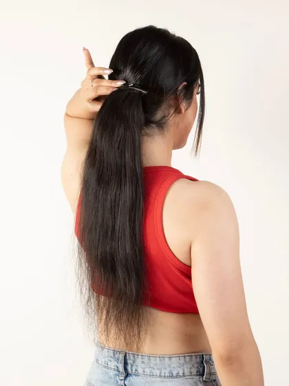 A model adjusting her ponytail extension, creating a natural, in-use lifestyle shot.