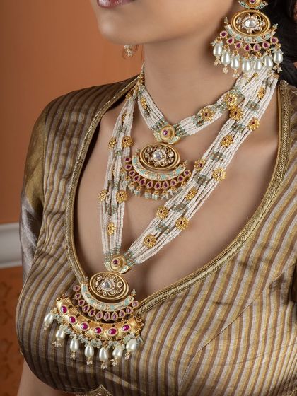 A detailed shot of the layered Kundan pearl necklaces. The intricate pendants and beadwork are a testament to the rich traditions of Indian jewellery making.