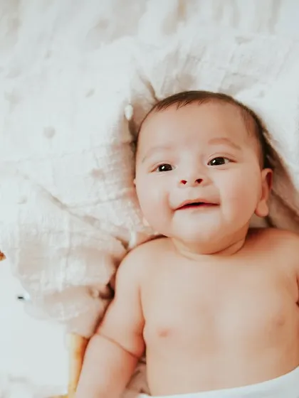 A happy four-month-old smiling from his cozy basket. Milestone sessions are perfect for capturing their budding personality as they learn to smile and interact with the world.