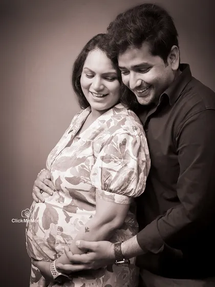 A beautiful moment of togetherness, captured in a warm sepia tone. This classic portrait shows the couple embracing, their smiles reflecting the shared happiness of their pregnancy journey.