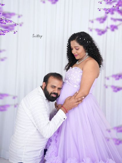 A sweet couple portrait with the husband-to-be listening to the baby bump. The lavender ruffled gown and floral framing add a whimsical and romantic touch.