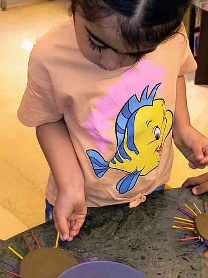 This little artist is deciding where to place the next colorful ray on her clay sun. It's a great exercise in concentration and design.