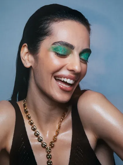A beautiful, smiling close-up that showcases the glittery green eyeshadow and the luminous skin.