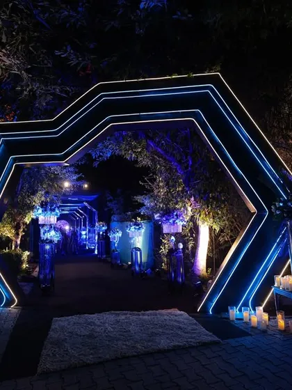 The geometric neon entrance arch, flanked by clusters of candles, created a stunning and futuristic welcome for guests.