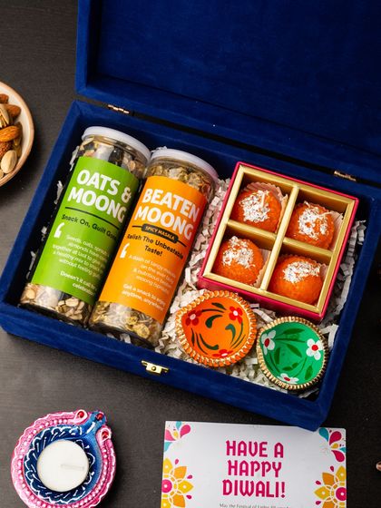 A healthy and traditional Diwali gift, this blue velvet box contains jars of oats and moong, beaten moong, and a box of motichoor ladoos, accompanied by hand-painted diyas.