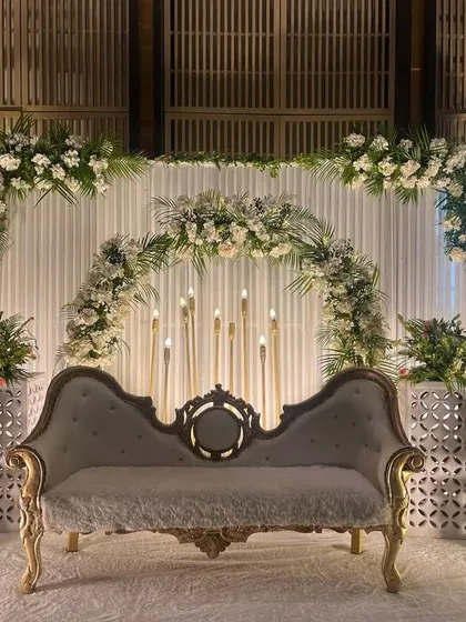 A clean and classic engagement stage with white florals, greenery, and elegant candle stands. This minimalist design is perfect for a sophisticated celebration.