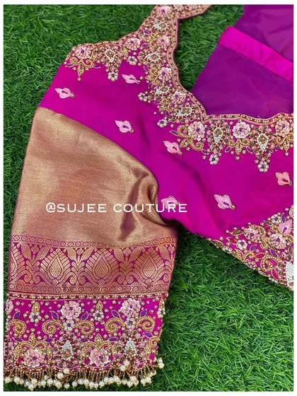 A rich magenta blouse with contrasting gold brocade sleeves. The body of the blouse is heavily embroidered with floral zardozi work, and the sleeve cuffs feature pearl tassels.