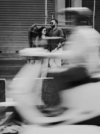 The same motion blur concept captured in timeless black and white. The moving scooter creates a dynamic streak of light, contrasting with the couple's still embrace.