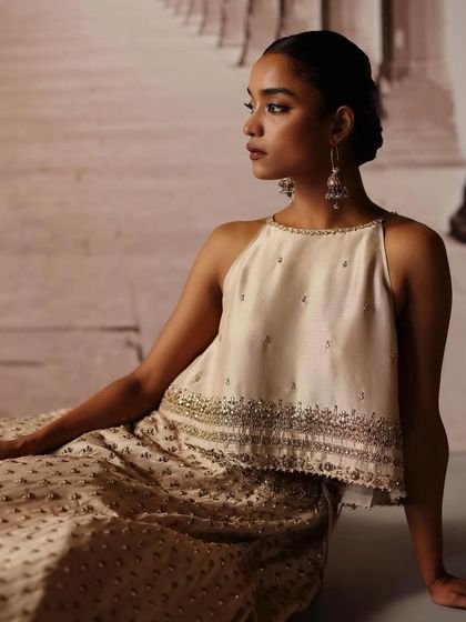 A close-up on a halter-neck blouse with delicate embroidery. The styling is focused on creating a refined and modern look, complemented by subtle, elegant jewelry.
