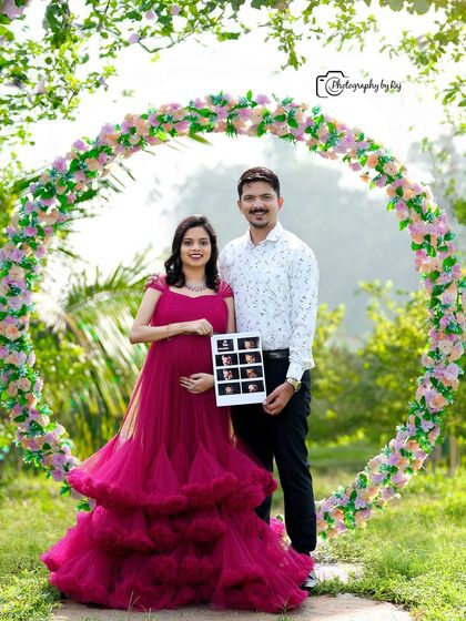 A happy couple's portrait holding a sonogram, framed by a circular floral prop.