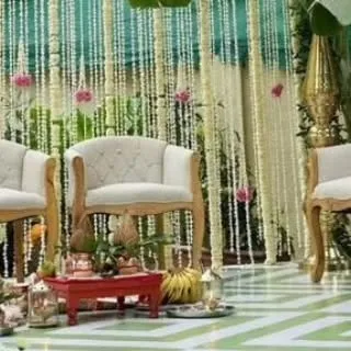 This image shows the seating arrangement within a traditional mandap. The elegant chairs are set against a backdrop of hanging floral strings, creating a beautiful and authentic ceremony space.
