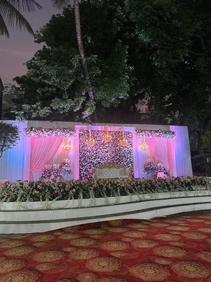 The reception stage at dusk, where our lighting design begins to transform the atmosphere, making the floral wall and chandeliers glow.