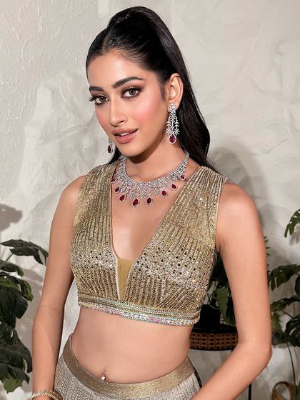 A full-body shot of the golden glam look. The sleek high ponytail and shimmering lehenga make this a perfect outfit for a sangeet or reception guest.