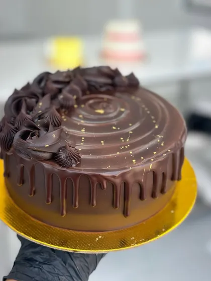 A close-up of a rich, decadent chocolate drip cake, one of the many popular designs we teach. You will learn to create this glossy ganache, master the drip technique, and pipe beautiful chocolate swirls for a truly professional finish.